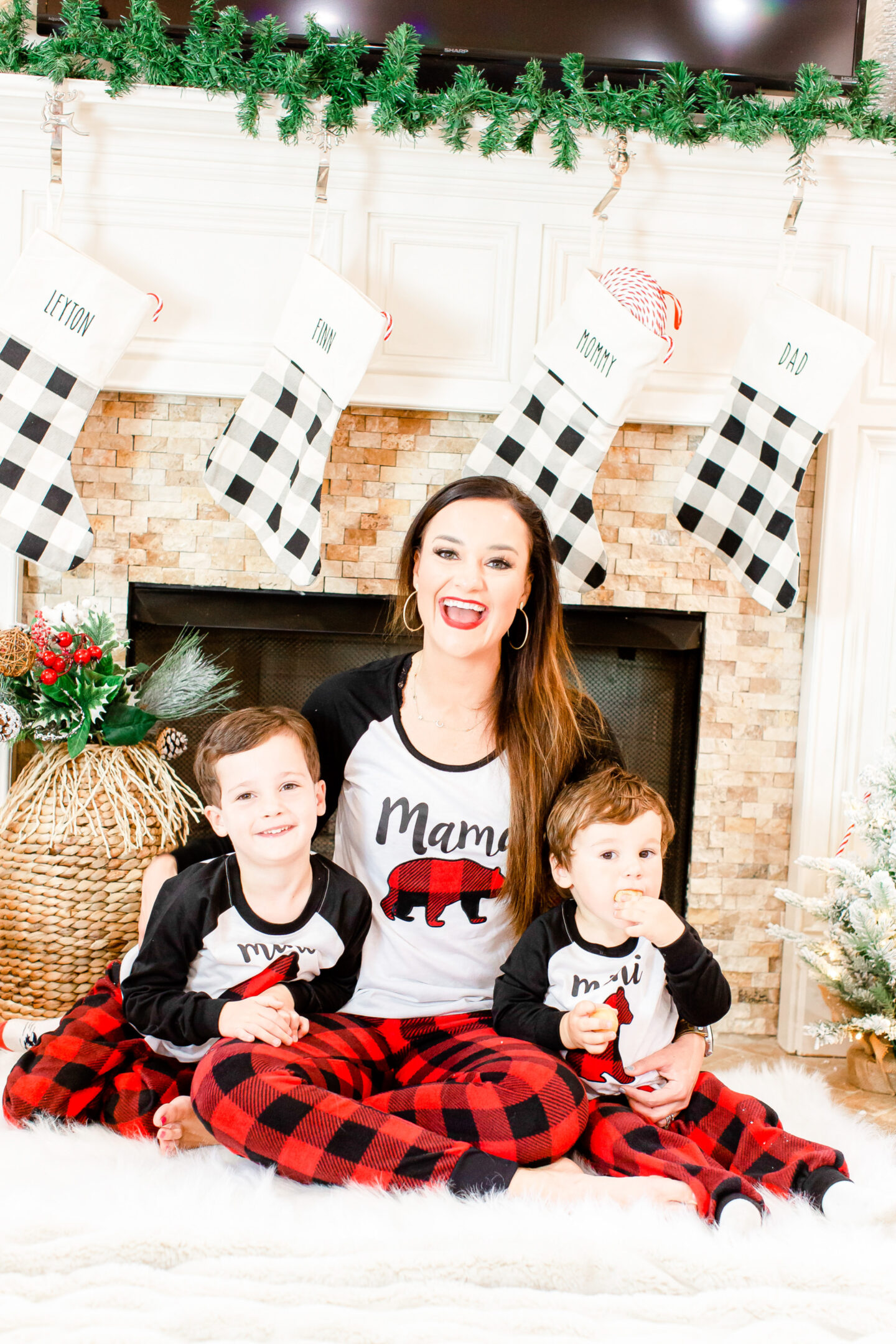 Entertain The Kids During The Busy Holiday Season With This Great Gift Idea For Kids: Heather sits with her sons in front of a fireplace wearing matching pajamas