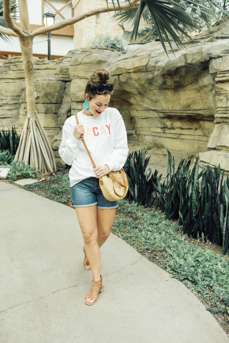 A Complete Dallas Travel Guide featured by top US travel blog, My Life Well Loved: image of a woman in Dallas wearing a Pink Lilly sweatshirt, Liverpool denim shorts, Marleylilly crossbody bag , Accessory Concierge statement earrings, zeroUV square sunglasses and Comfortiva sandals