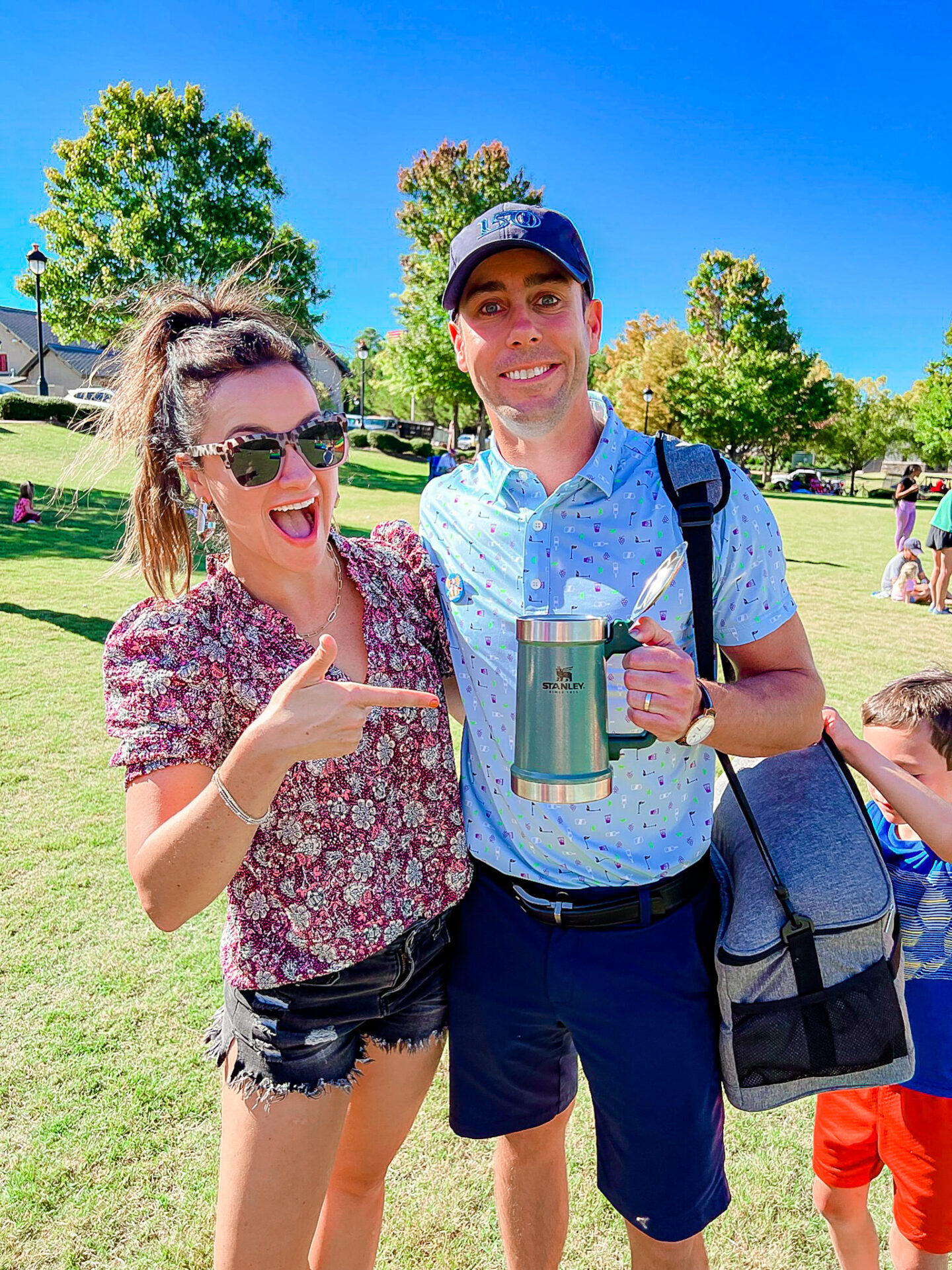 Heather and Eric are smiling at the camera, dressed in summer clothes. Eric is holding a Stanley cup. 