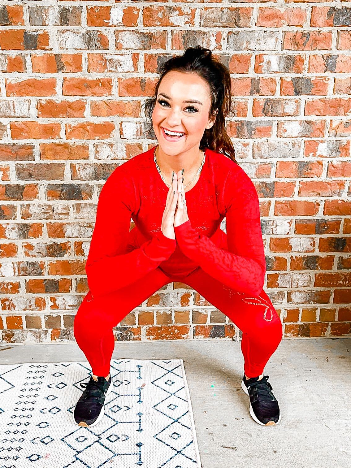 Heather is exercising in a red matching athletic set and black sneakers. 